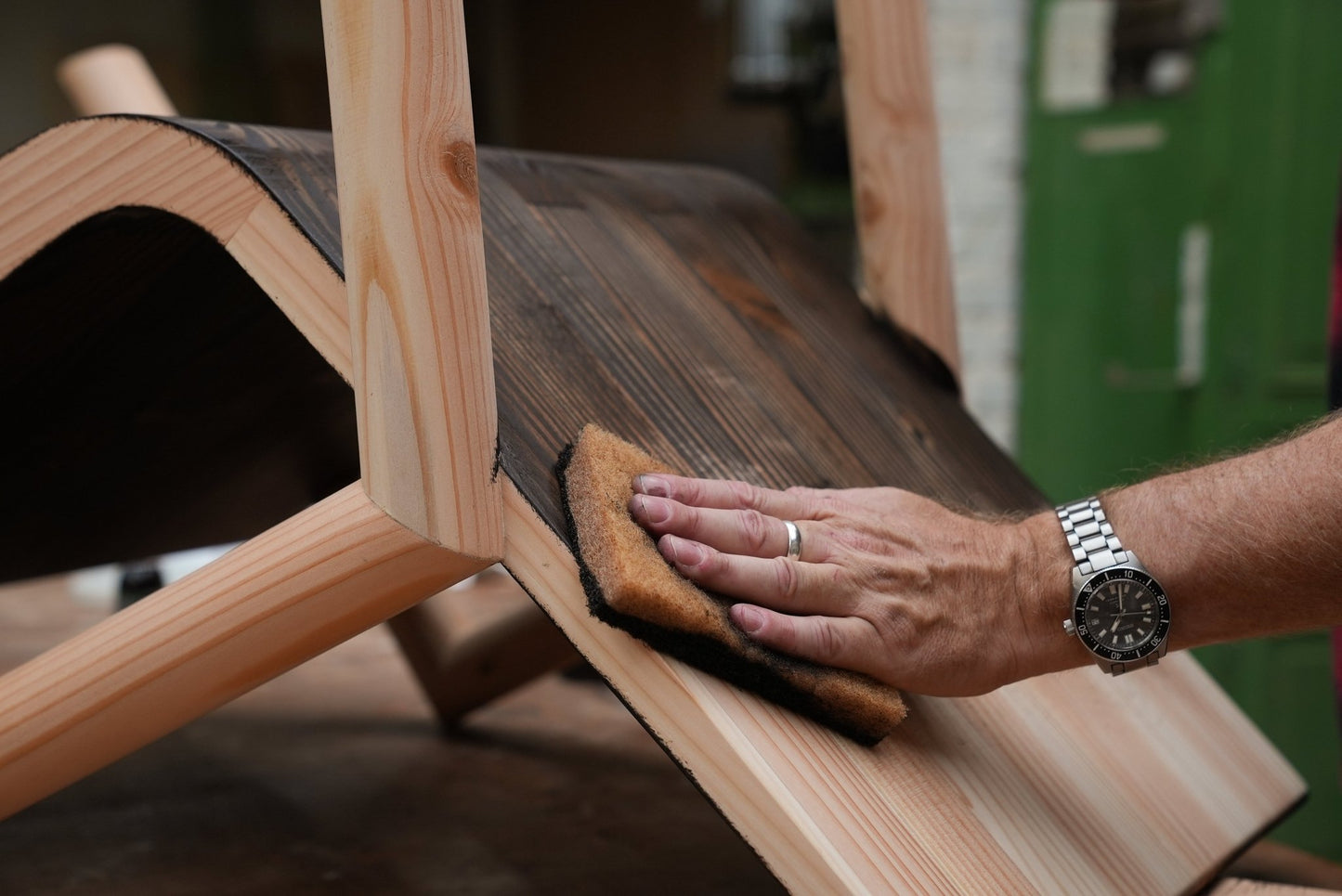 Person oiling a wooden chair with a pad